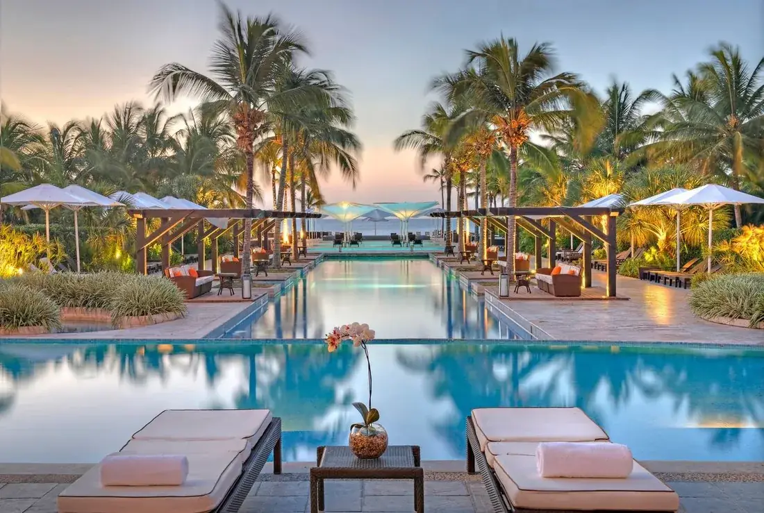 Piscina larga entre palmeras al atardecer en Buenaventura