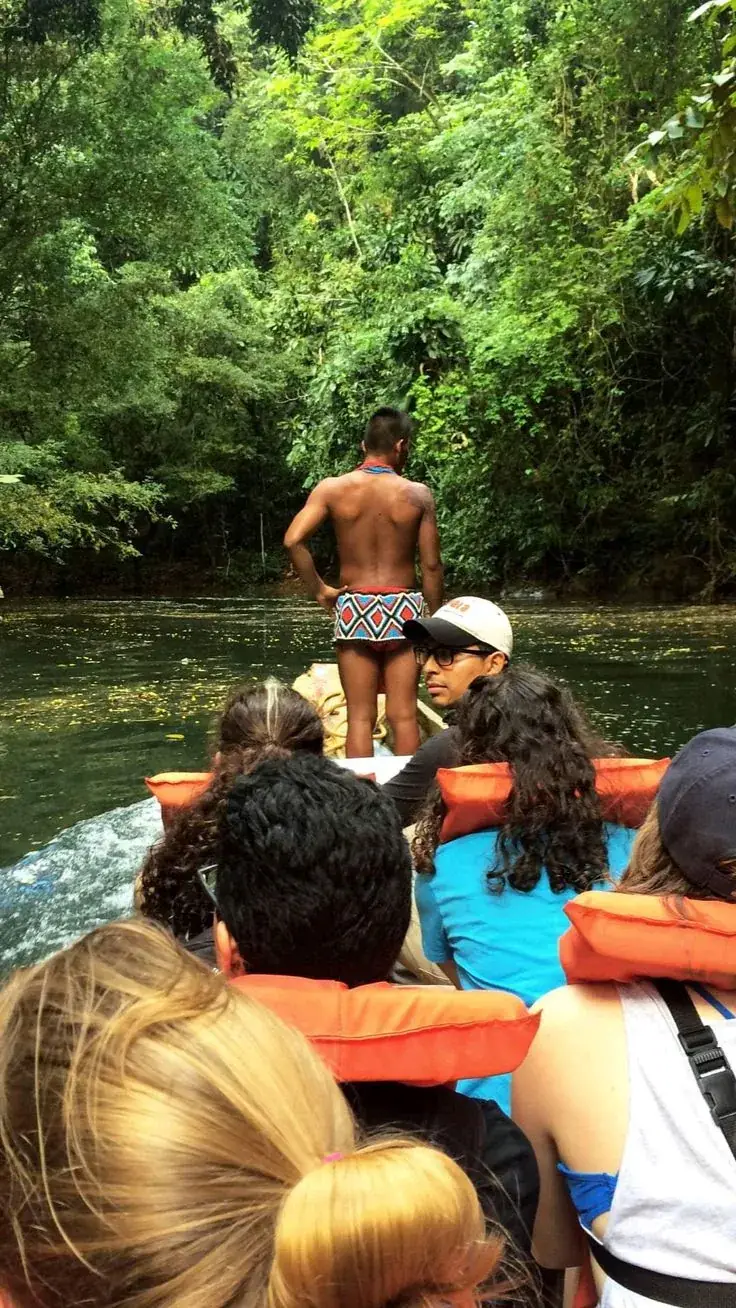 Viajeros con chalecos salvavidas en una piragua; un guía emberá va de pie en la proa