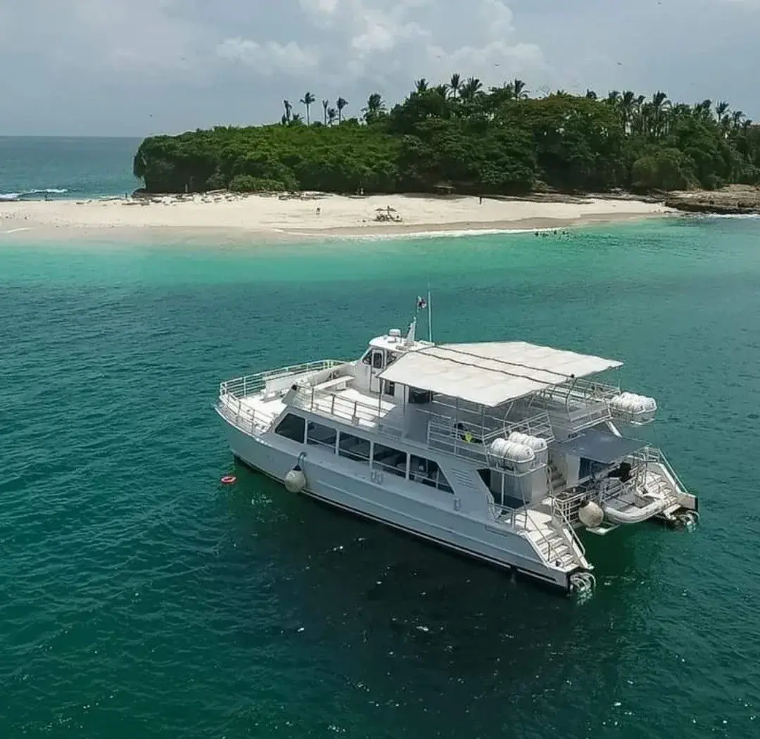 Un catamarán blanco anclado frente a una isla con un banco de arena