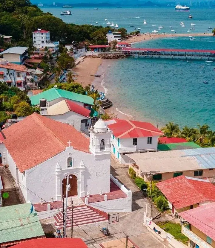 Vista aérea de la iglesia blanca de Taboga, los techos rojos y el muelle