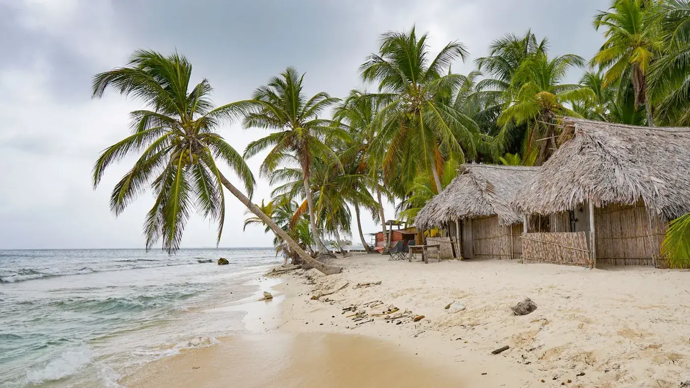 Cabañas de techo de palma entre cocoteros, en una playa de Guna Yala