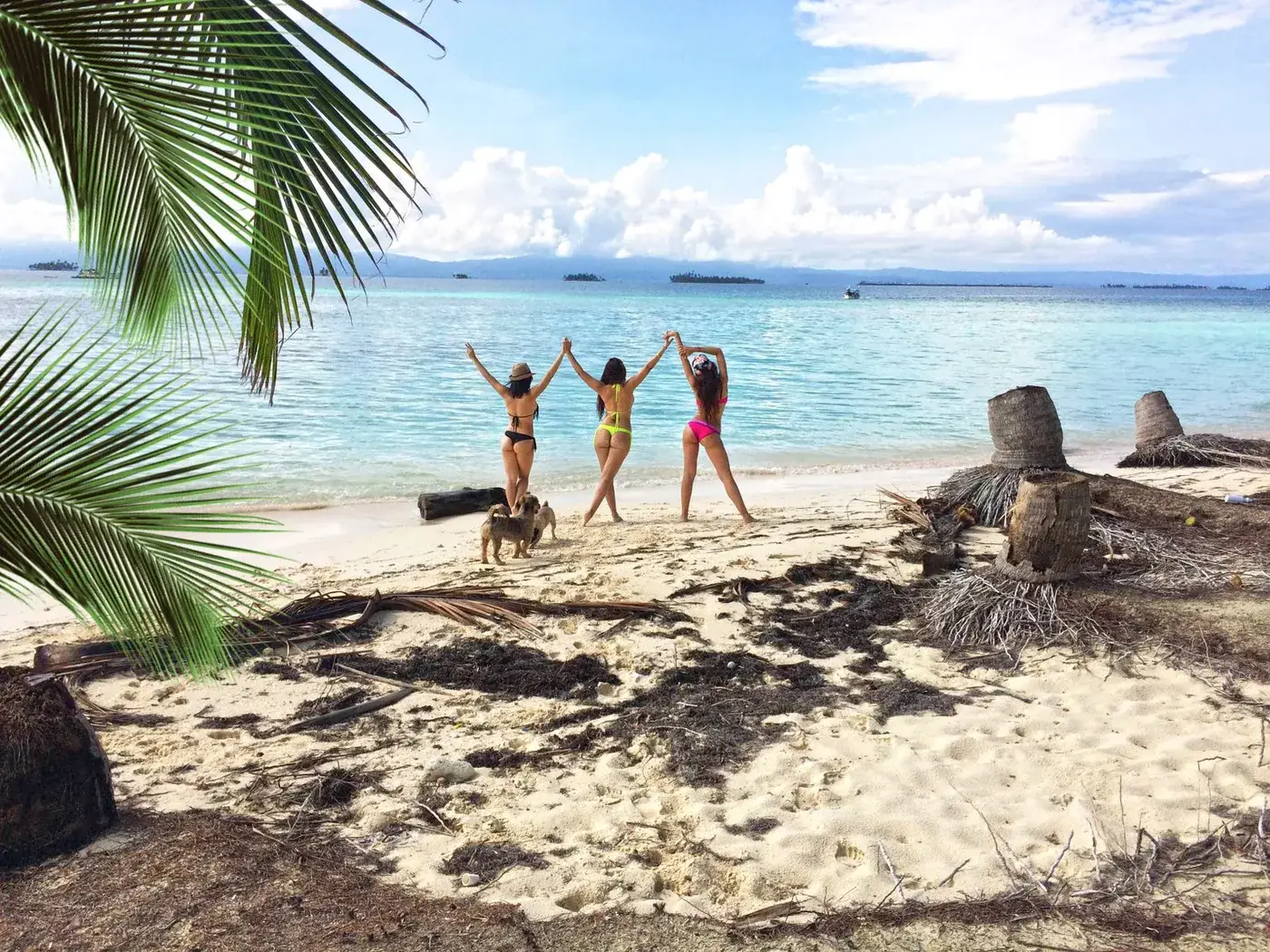 Tres viajeras celebran en la orilla de una playa de arena blanca en Guna Yala
